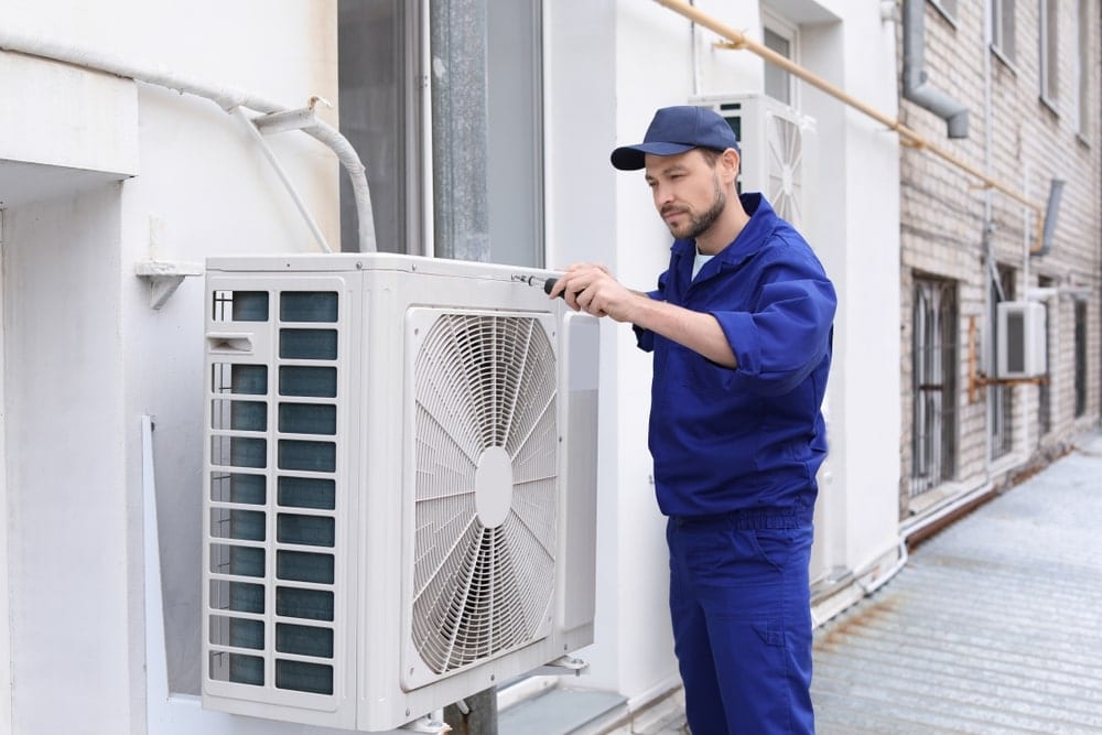 technician-in-bluesuit-checking-outdoor-ac-unit